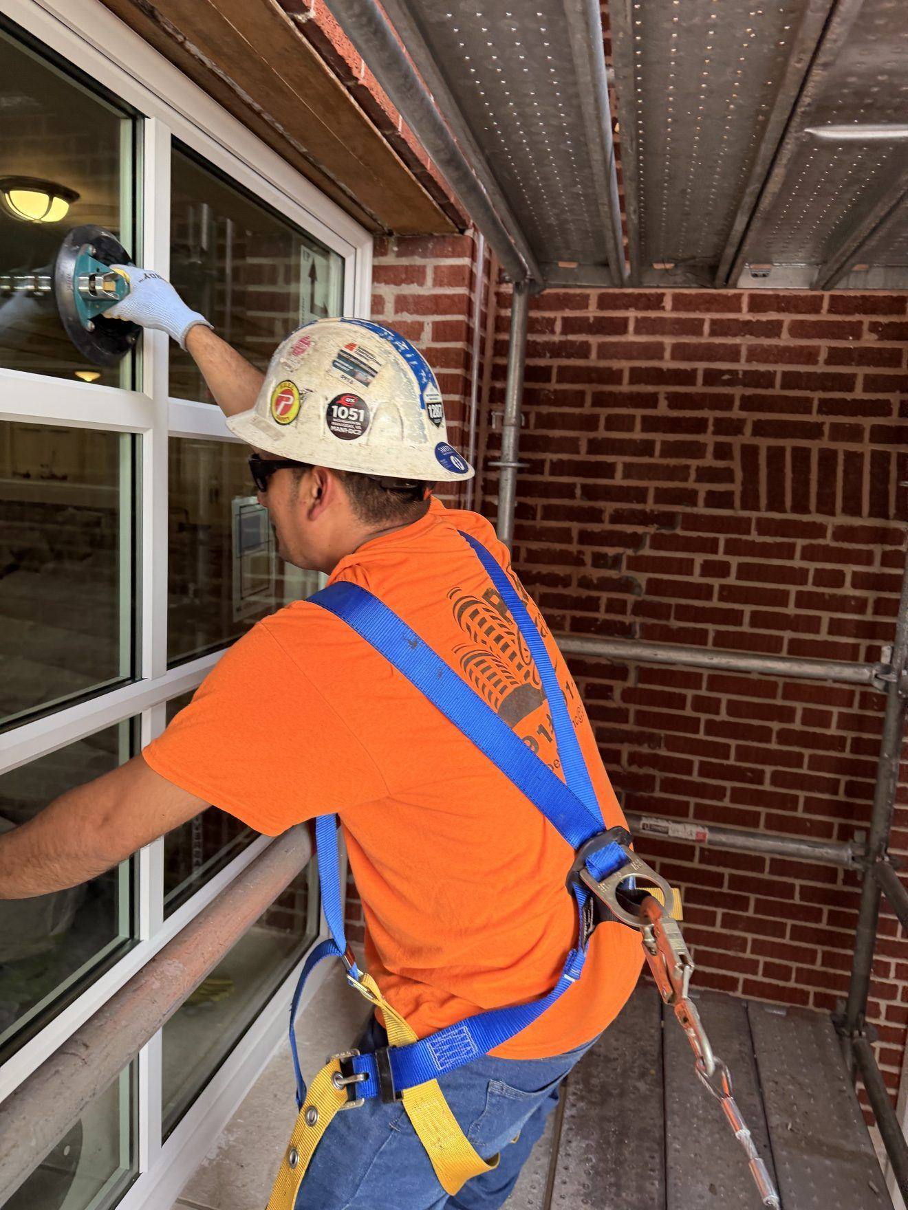 Glazier setting a window — hard hat and harness
